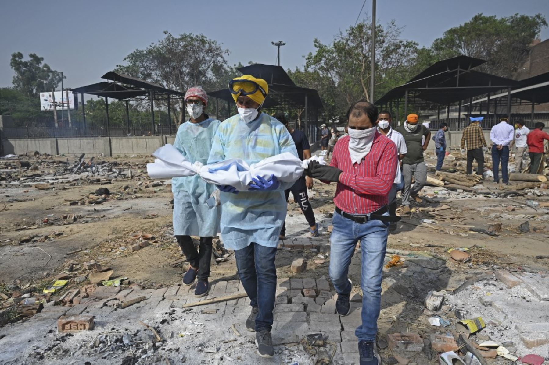 Un voluntario lleva el cuerpo de un niño que murió de coronavirus covid-19 para los últimos ritos en un crematorio en Nueva Delhi. Foto: AFP
