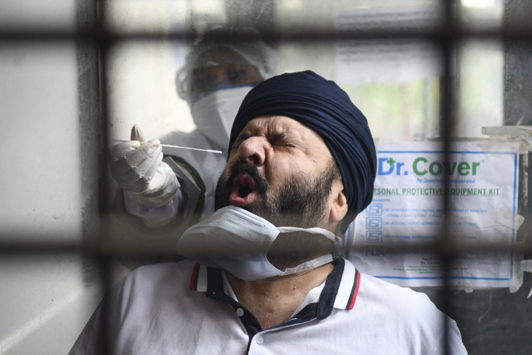 Un trabajador de la salud toma una muestra de un hisopo nasal de un hombre para realizar la prueba del coronavirus Covid-19 en un hospital civil en Amritsar. Foto: AFP