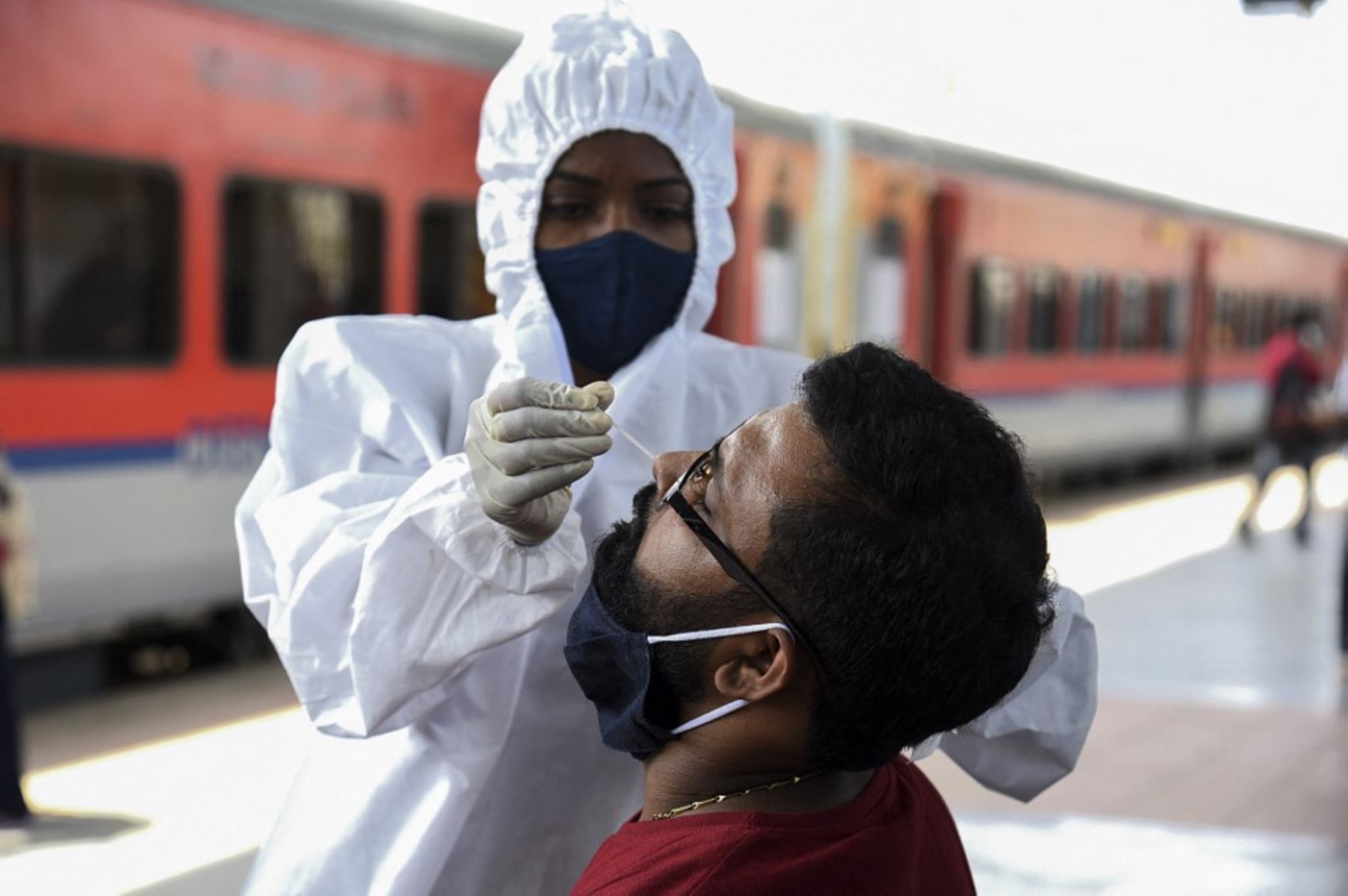 Un trabajador de la salud toma una muestra de un hisopo nasal de un pasajero para analizar el coronavirus Covid-19 después de llegar a una plataforma ferroviaria en un tren de larga distancia, en Mumbai. Foto: AFP