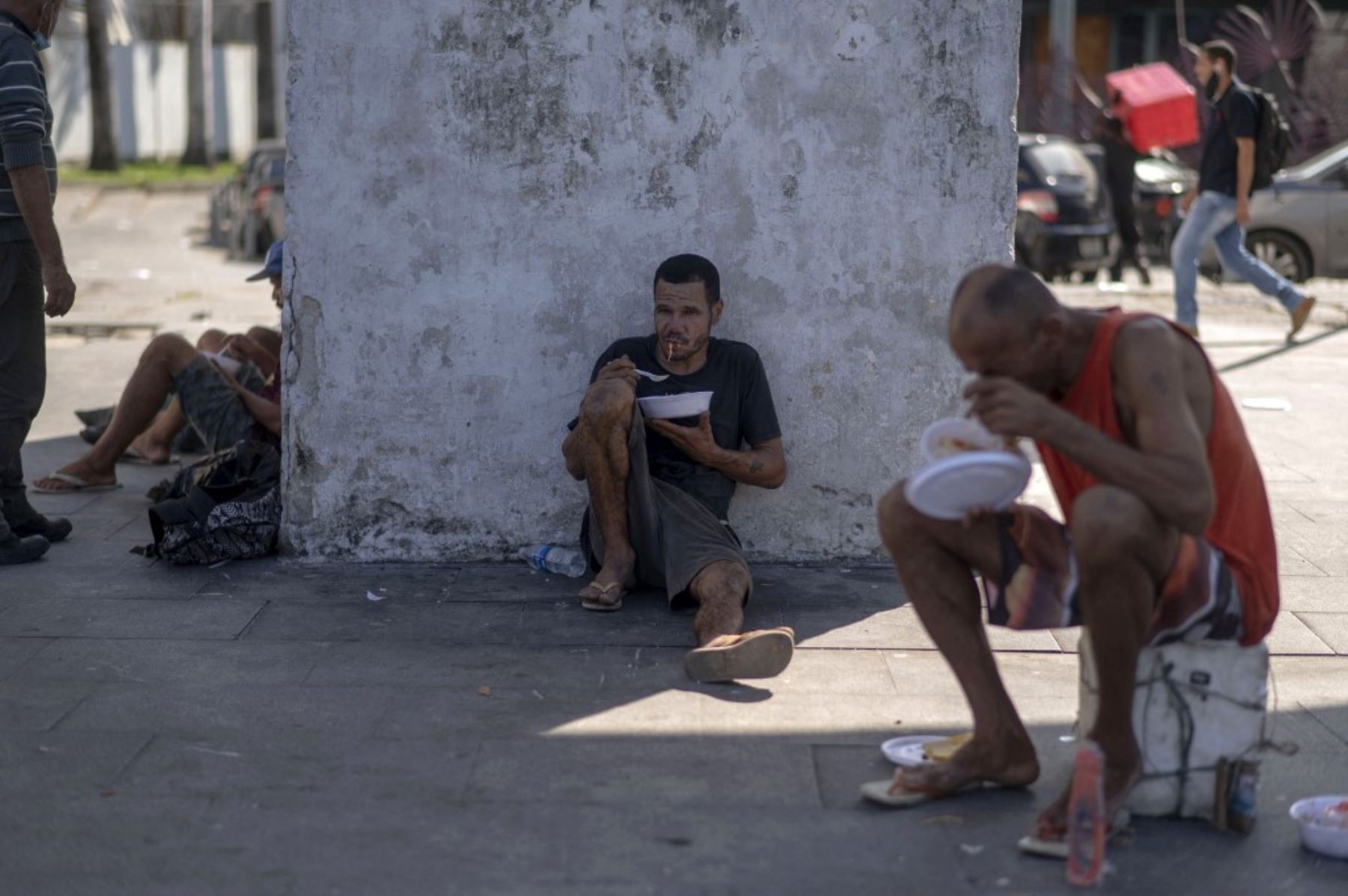 Hombres sin hogar comen una comida que les dio el proyecto Covid Sem Fome (Covid Sin Hambre) en el atractivo turístico internacionalmente conocido de Los Arcos de Lapa, en el centro de Río de Janeiro, Brasil. Foto: AFP