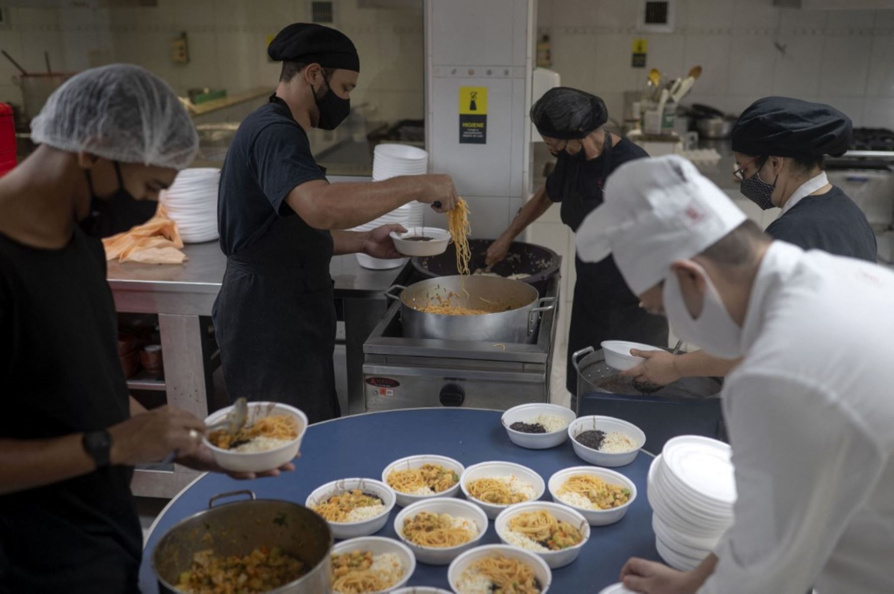 Voluntarios del proyecto Covid Sem Fome (Covid Sin Hambre) sirven comidas para personas sin hogar dentro de la cocina profesional de la Universidad Augusto Motta (UNISUAM) en el barrio Bonsucesso, norte de Río de Janeiro, Brasil. Foto: AFP