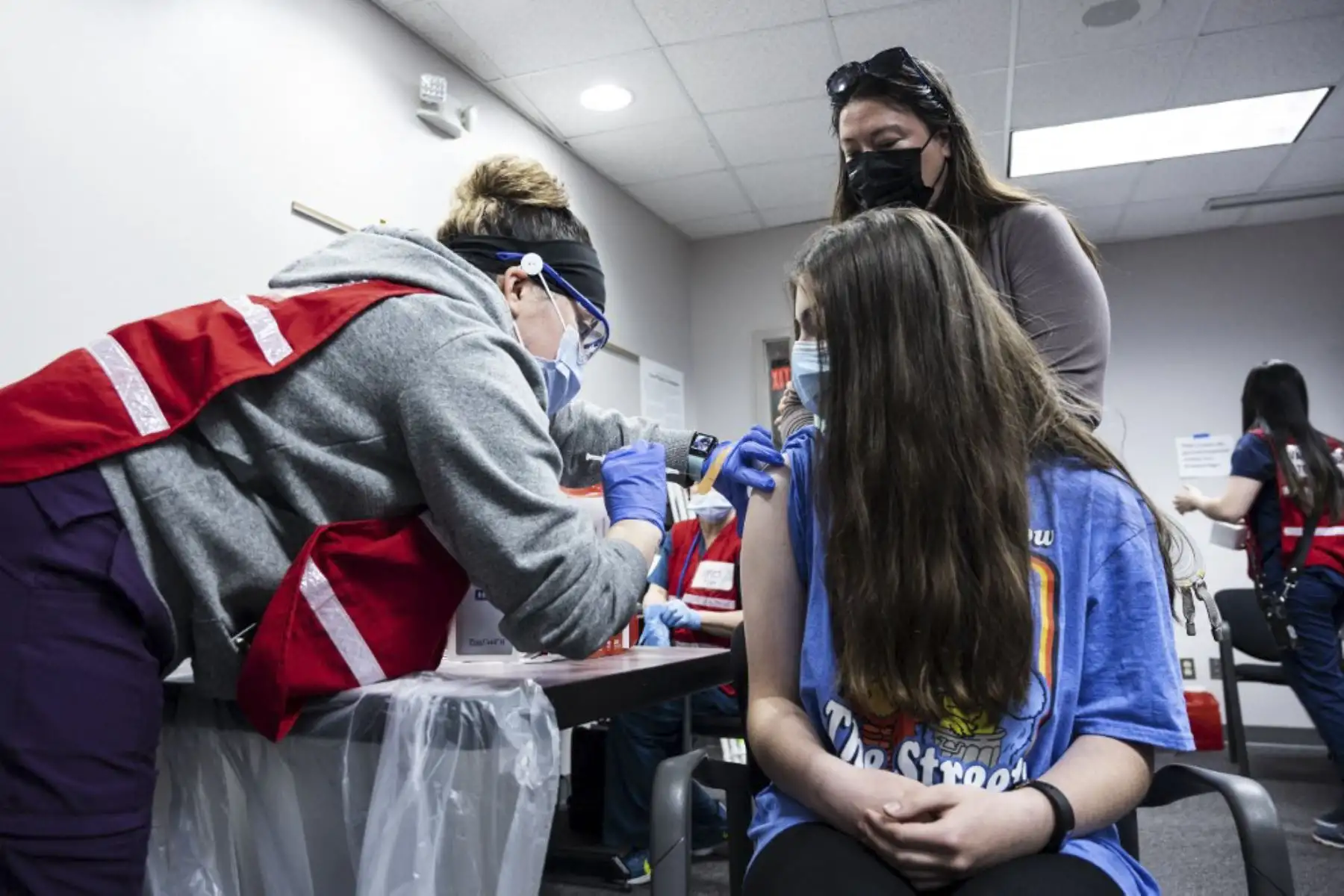 Una madre observa cómo su hija recibe la vacuna Covid-19 en la clínica de vacunación del Fairfax Government Center en Fairfax, Virginia. Foto: AFP