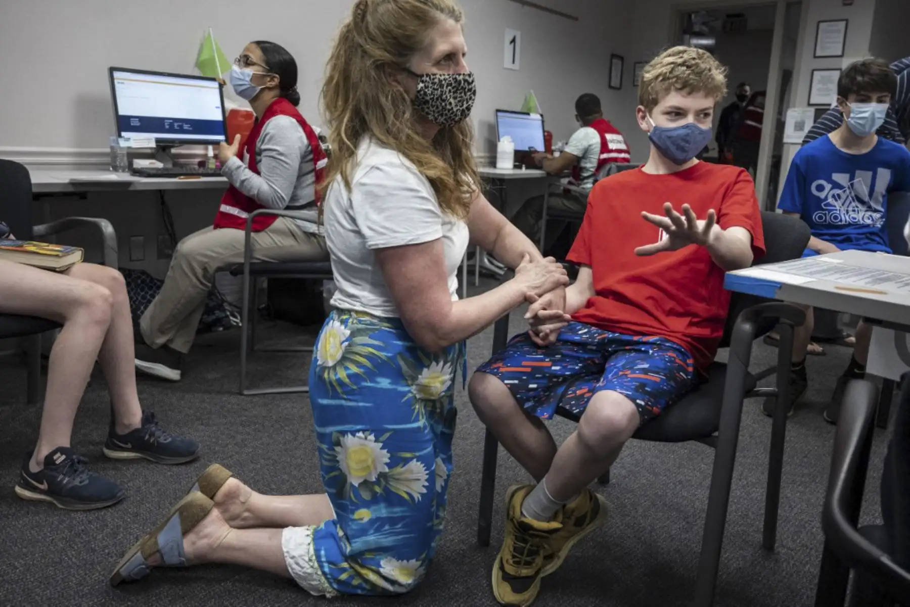 Elizabeth Brauer sostiene la mano de su hijo Luke Brauer, de 13 años, antes de que reciba la vacuna Covid-19 en la clínica de vacunación del Fairfax Government Center en Fairfax, Virginia. Foto: AFP