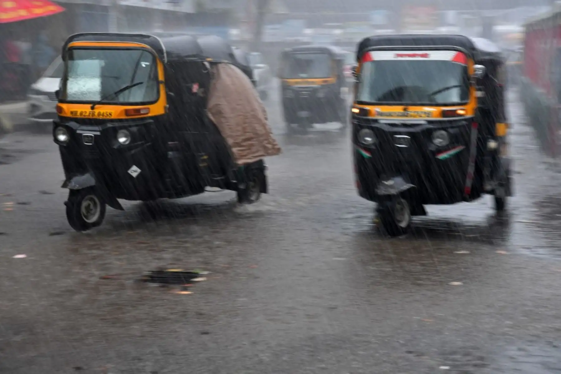 Mototaxis conducen por una calle en medio de las fuertes lluvias del ciclón Tauktae en Mumbai el 17 de mayo de 2021