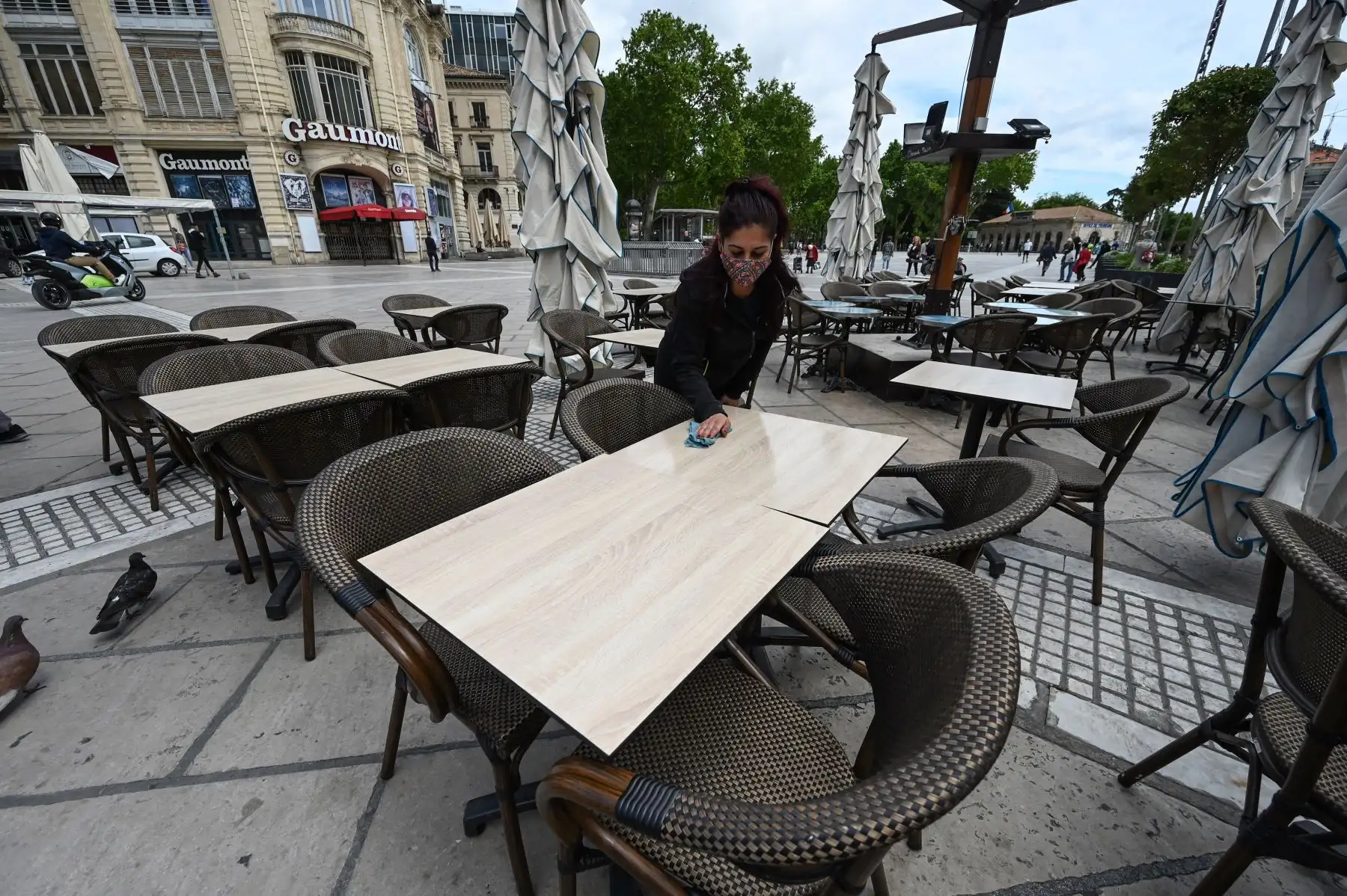 Una mujer instala la terraza de un restaurante en la ciudad de Montpellier, en el sur de Francia, el 17 de mayo de 2021, dos días antes de una reapertura enormemente anticipada de las terrazas de los restaurantes, parte de un alivio del cierre nacional. Foto: AFP
