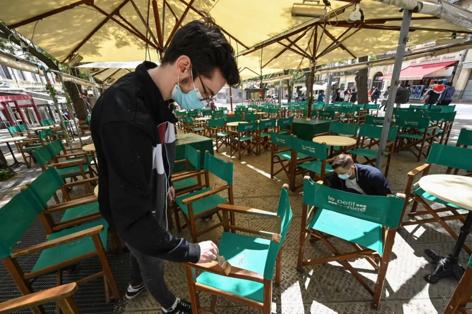 Dos hombres instalan la terraza de un restaurante en la ciudad de Montpellier, en el sur de Francia, el 17 de mayo de 2021, dos días antes de una reapertura enormemente anticipada de las terrazas de los restaurantes, parte de un alivio del cierre nacional. Foto: AFP