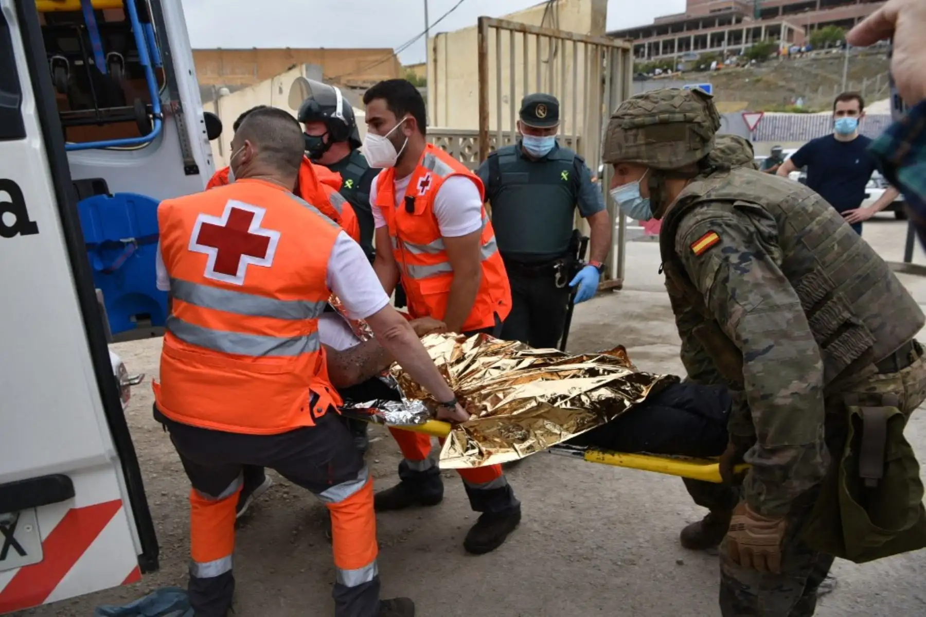Cruz Roja y soldados españoles llevan a un migrante que llegó nadando al enclave español de Ceuta en una ambulancia el 18 de mayo de 2021 en Ceuta. - España ha devuelto a Marruecos casi la mitad de los 6.000 migrantes que entraron en su enclave de Ceuta, mientras cientos más intentaban entrar en su otro territorio del norte de África. Foto: AFP