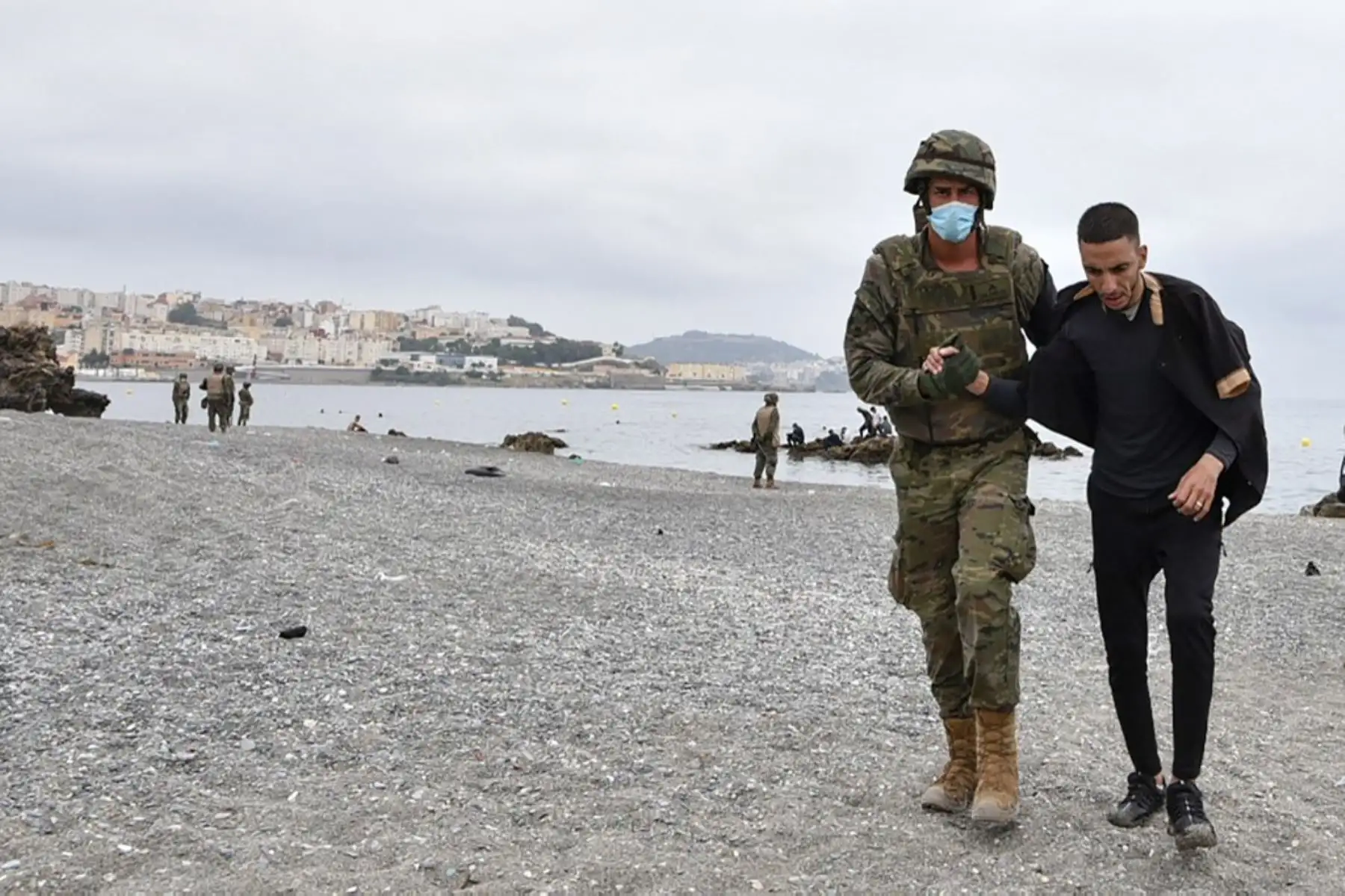 Un soldado español asiste a un migrante que llegó nadando al enclave español de Ceuta, el 18 de mayo de 2021 en Ceuta. - España ha devuelto a Marruecos casi la mitad de los 6.000 migrantes que entraron en su enclave de Ceuta, mientras cientos más intentaban entrar en su otro territorio del norte de África. Foto: AFP
