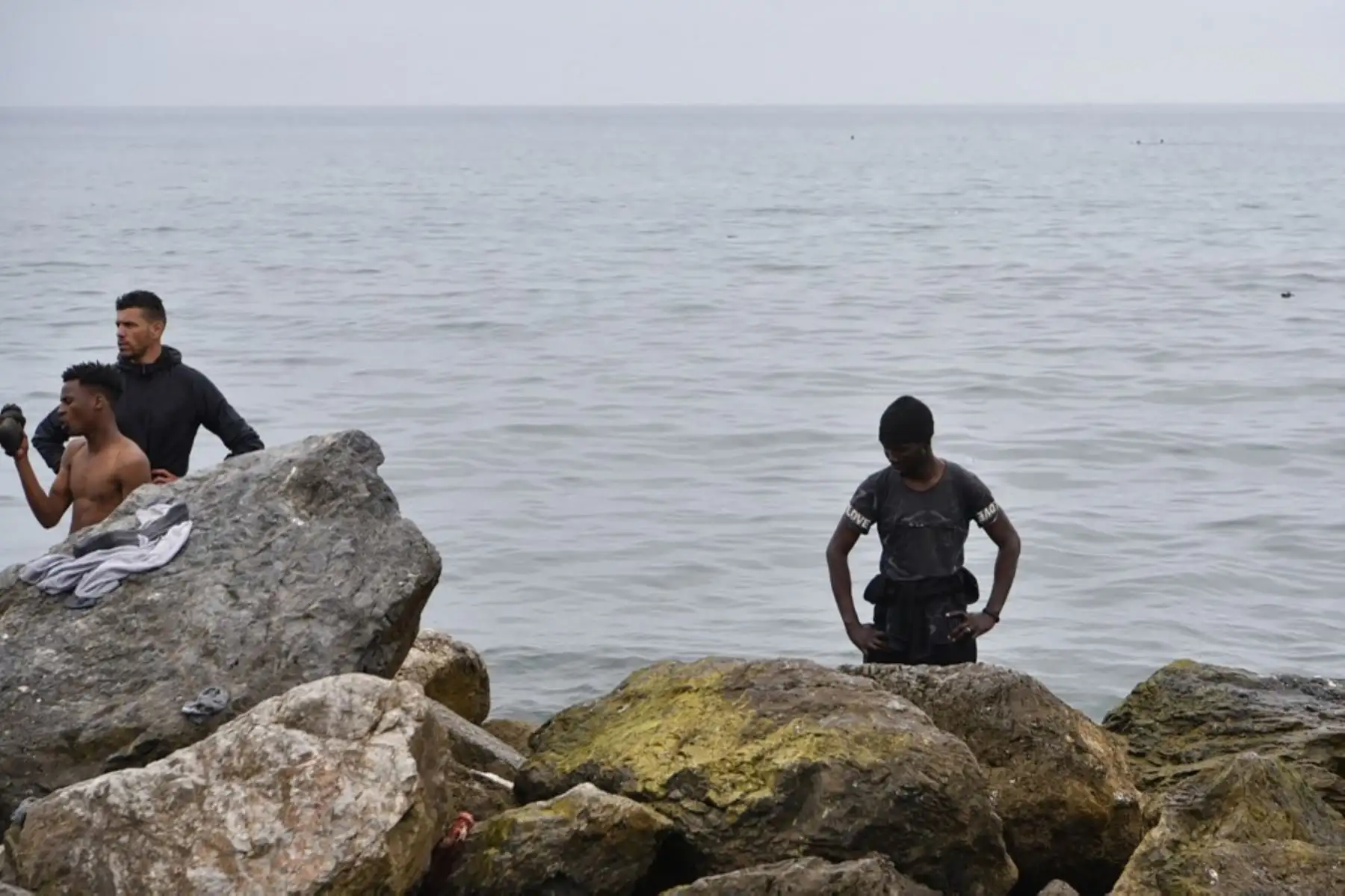 Los migrantes descansan tras nadar hasta el enclave español de Ceuta, el 18 de mayo de 2021 en Ceuta. - España ha devuelto a Marruecos casi la mitad de los 6.000 migrantes que entraron en su enclave de Ceuta, mientras cientos más intentaban entrar en su otro territorio del norte de África. Foto: AFP