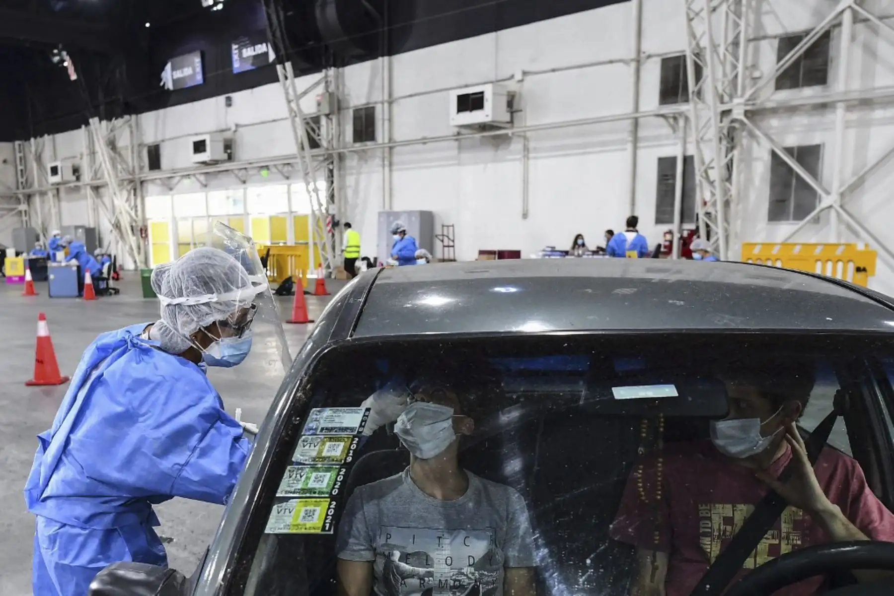 Un trabajador de salud recolecta muestras para la prueba de detección de casos de coronavirus covid-19 dentro de un automóvil, en el centro de convenciones Costa Salguero, en Buenos Aires. Foto: AFP