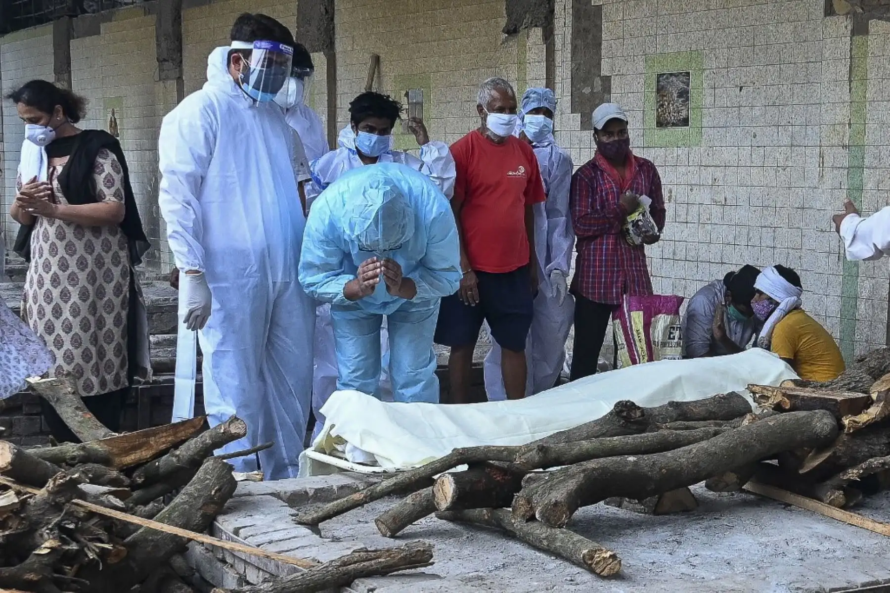 Familiares con trajes de Equipo de Protección Personal (EPP) realizan los últimos ritos por su ser querido, que murió debido al coronavirus Covid-19, en un crematorio en Nueva Delhi el 19 de mayo de 2021. Foto: AFP