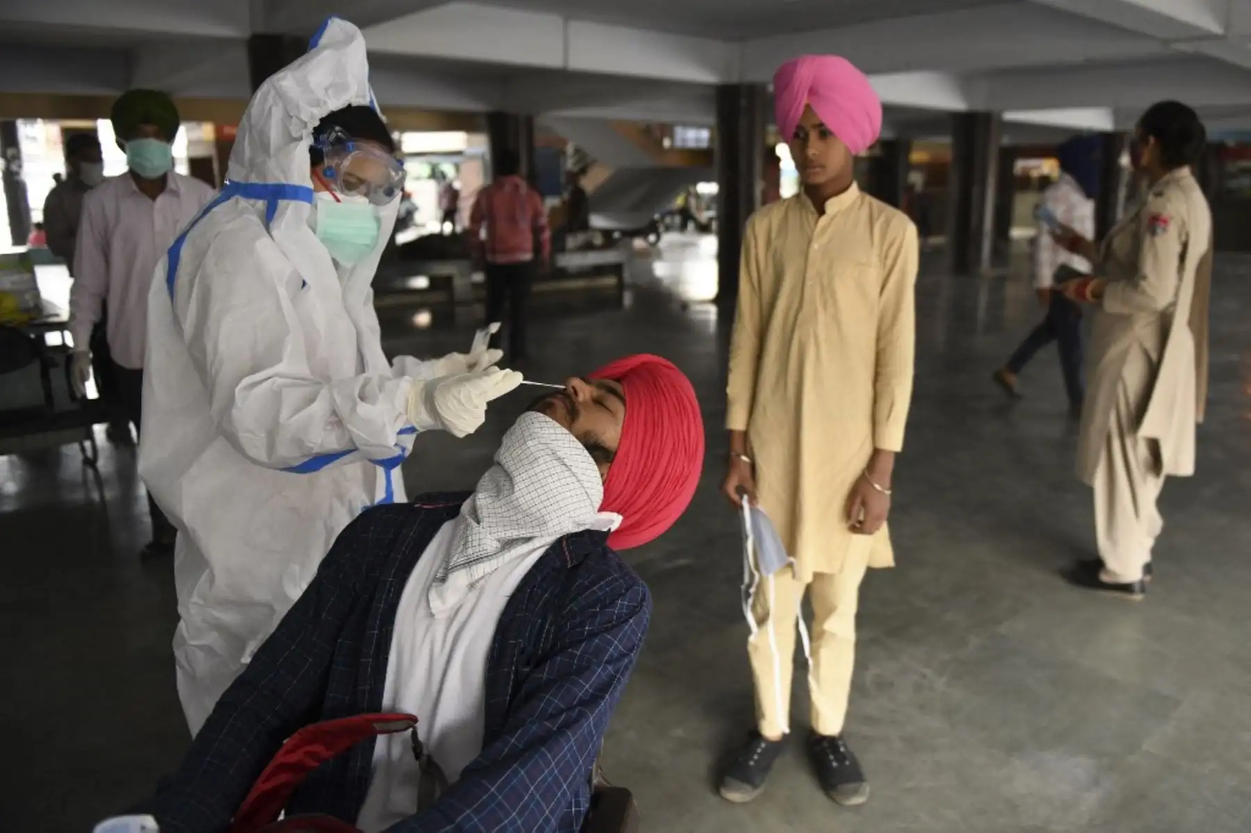 Un trabajador de la salud recolecta muestras de hisopos de los pasajeros para la detección del coronavirus Covid-19 en una terminal de autobuses en Amritsar el 19 de mayo de 2021. Foto: AFP