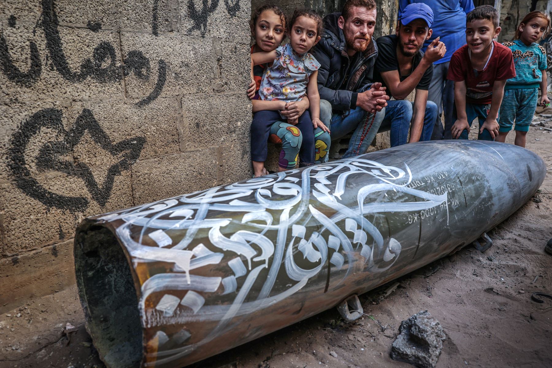 Palestinos miran los dibujos del artista Bilal Khaled en un cohete sin detonar en la ciudad de Gaza. Foto: AFP