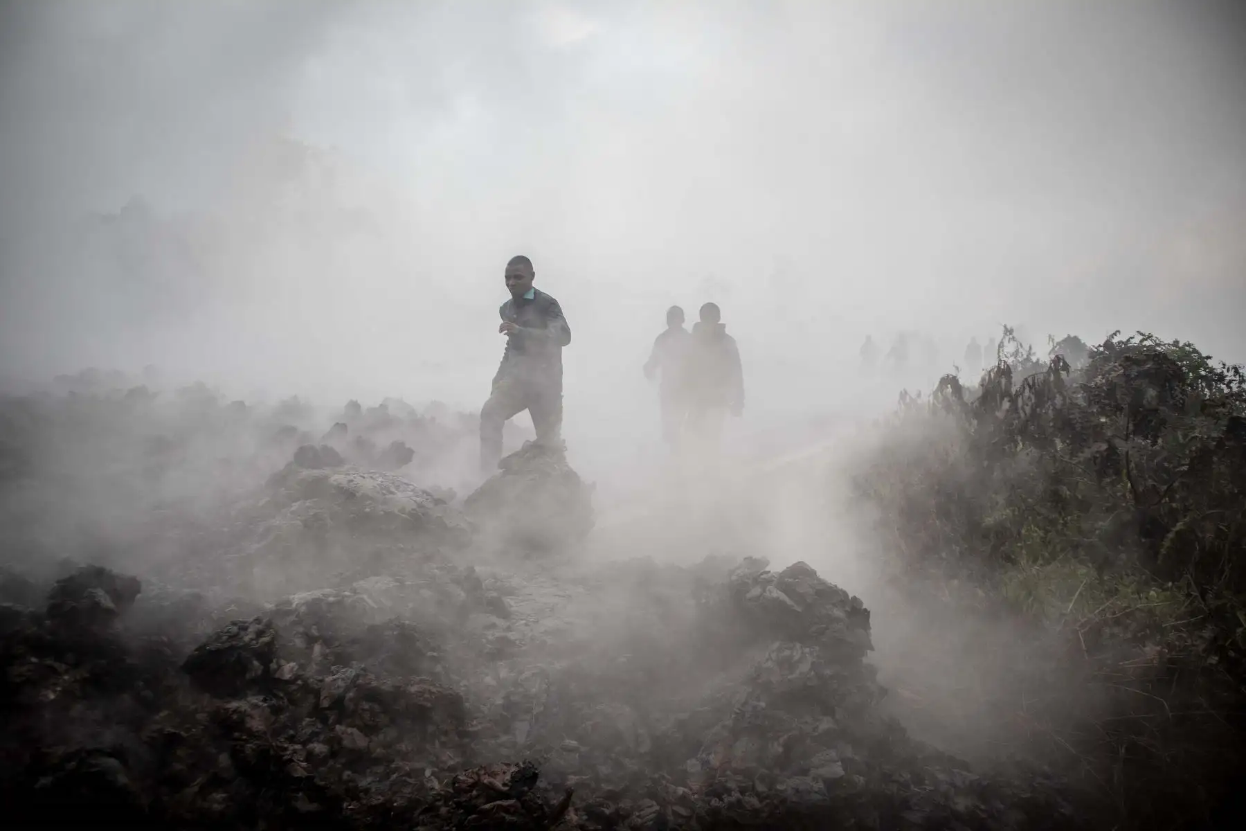 Hombres cruzan el frente de las rocas de lava aún humeantes de una erupción del monte Nyiragongo en Goma, en el este de la República Democrática del Congo. 
Foto: AFP