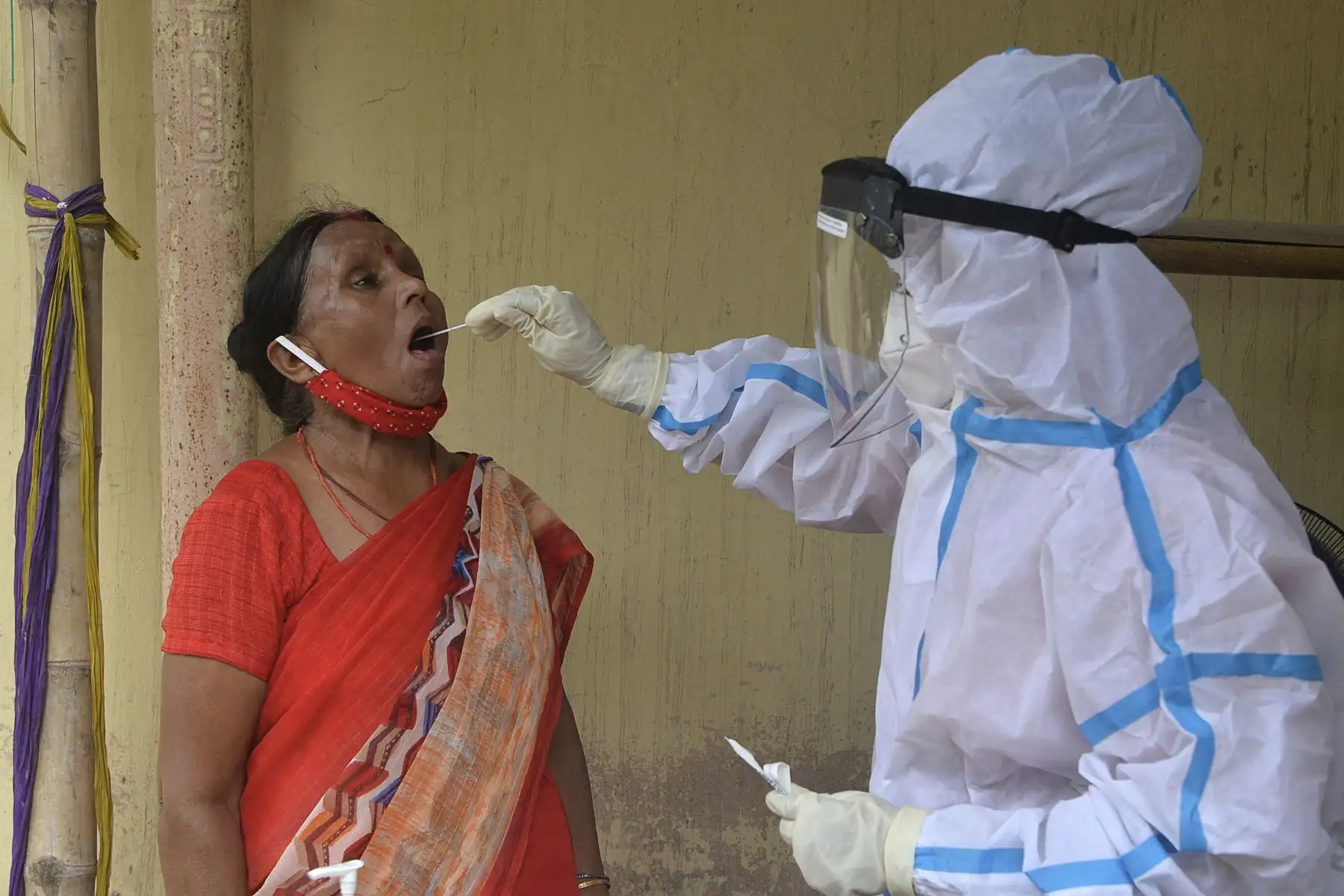 Un trabajador de la salud recolecta una muestra de hisopo de una mujer para realizar una prueba del coronavirus en un centro de salud primario en Siliguri, el 24 de mayo de 2021. Foto: AFP