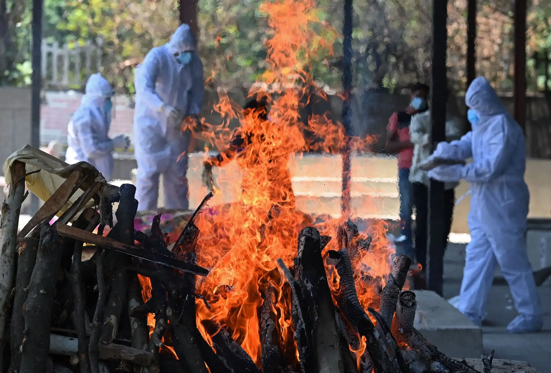 Los familiares y parientes que usan equipo de protección preparan una pira funeraria para incinerar a una víctima del coronavirus en un crematorio, en Nueva Delhi, el 24 de mayo de 2021. Foto: AFP