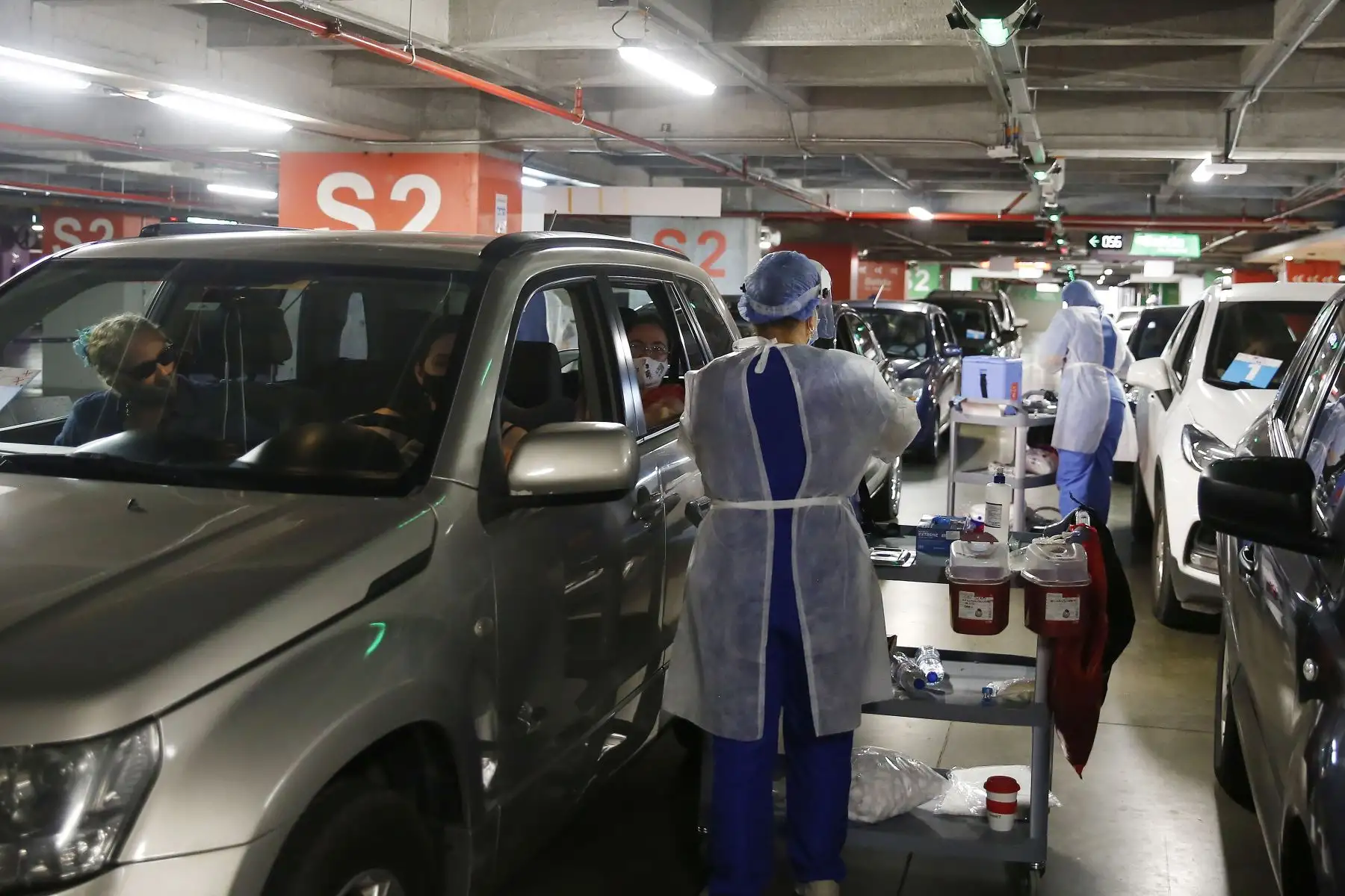 Varias personas reciben la vacuna contra la COVID-19 en un punto de vacunación vehicular instalado en uno de los centros comerciales de Medellín. Foto: EFE