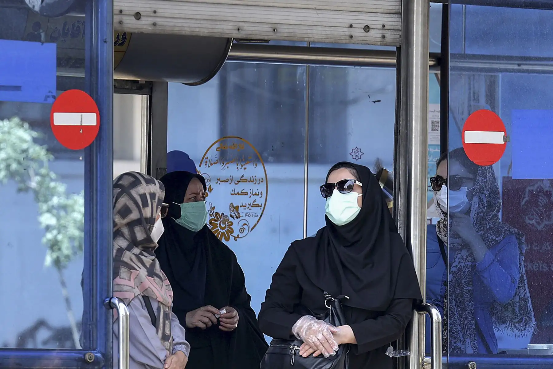 Mujeres iraníes, enmascaradas debido a la pandemia del coronavirus COVID-19, esperan en una estación de autobuses en la plaza Enghelab en el centro de la capital, Teherán, el 16 de mayo de 2021. Foto: AFP