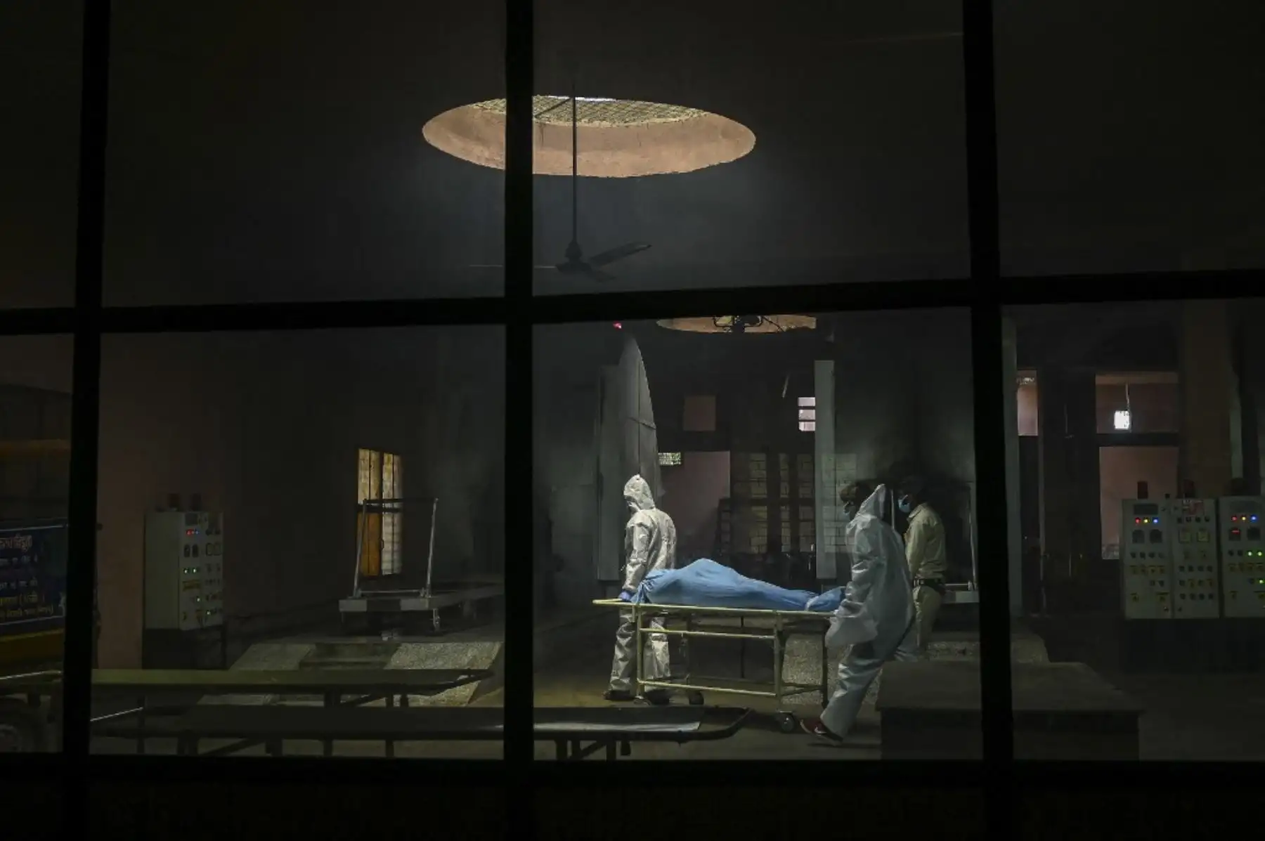 Personal de la ambulancia con trajes de equipo de protección personal (EPP) transporta el cadáver de una persona que murió debido al coronavirus covid-19, dentro de un crematorio en Nueva Delhi. Foto: AFP