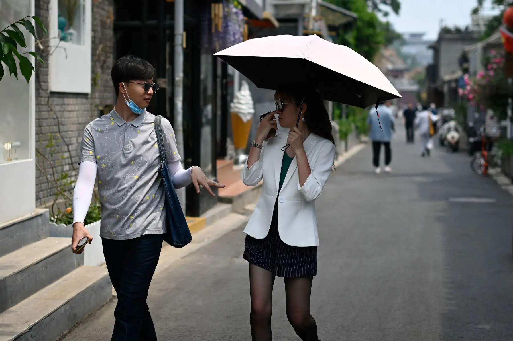 Un hombre conversa con una mujer mientras caminan por un callejón, en Beijing, el 19 de mayo de 2021, Foto: AFP