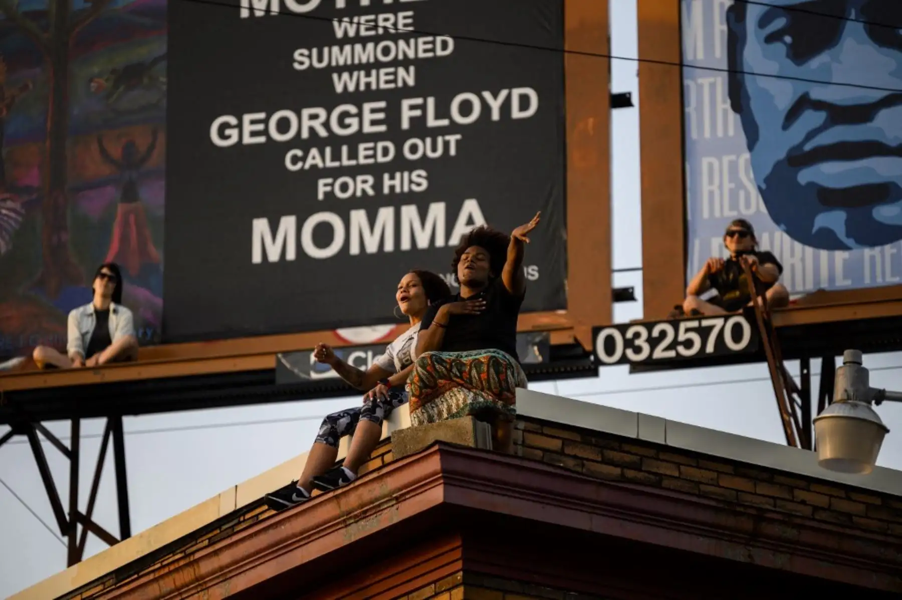 La gente observa desde el techo de un edificio mientras el grupo musical Sounds of Blackness se presenta en George Floyd Square en Minneapolis, Minnesota. Foto: AFP