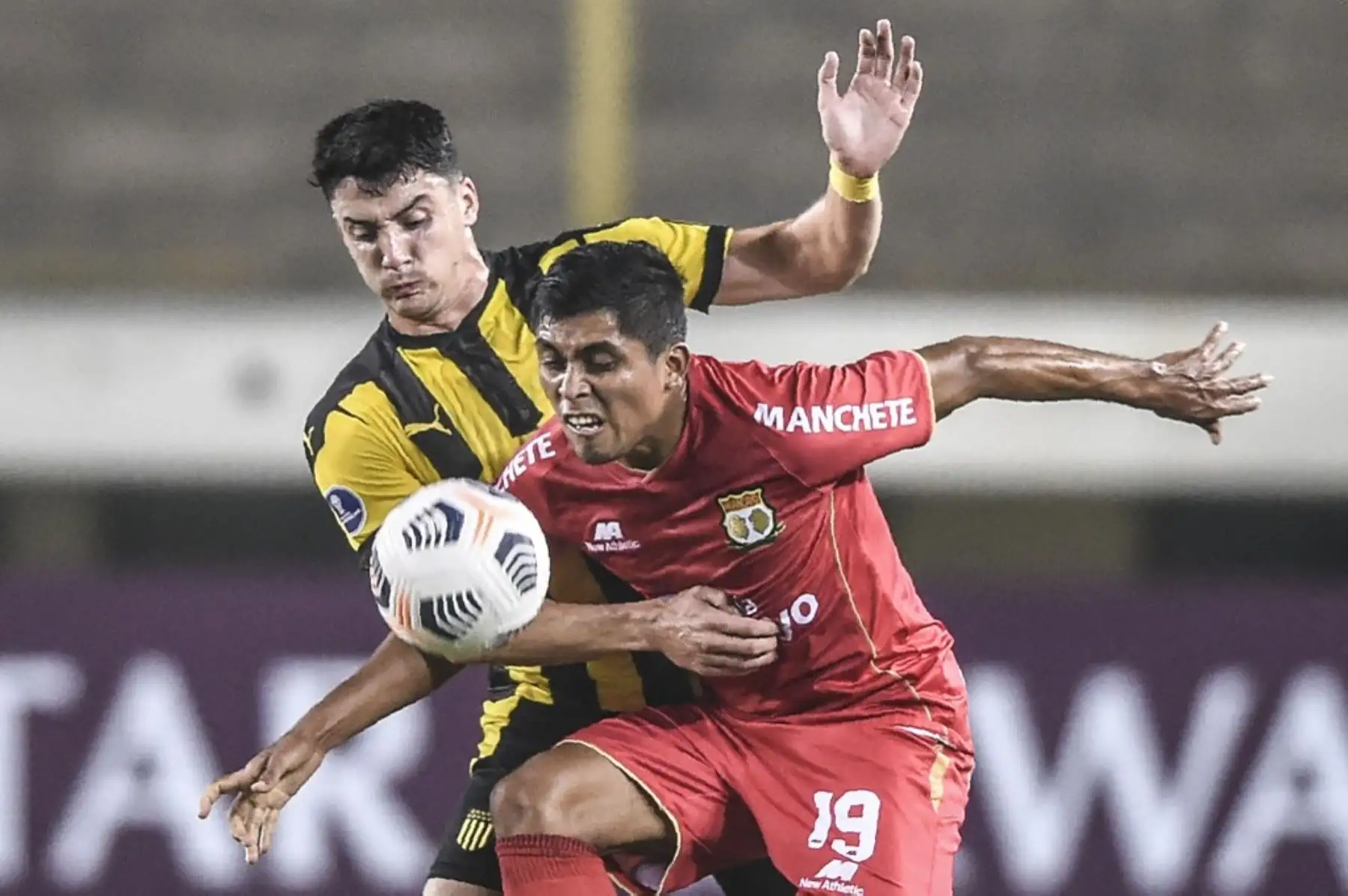 El peruano Sport Huancayo Ronal Huaccha y el uruguayo Peñarol Joaquín Piquerez compiten por el balón durante el partido de la fase de grupos del torneo de fútbol Copa Sudamericana en el Estadio Monumental de Lima. Foto: AFP