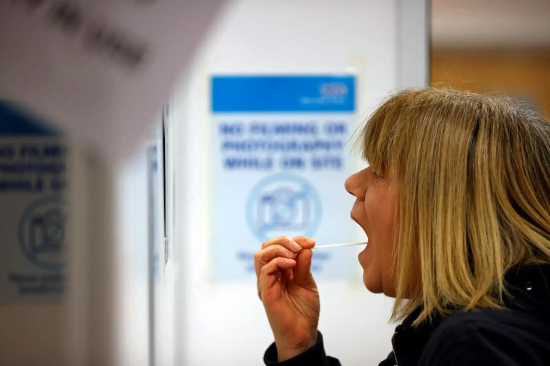 Una mujer usa un hisopo para tomar una muestra de su boca en una unidad de prueba NHS Test and Trace Covid-19 en el Civic Center en Uxbridge, Hillingdon, al oeste de Londres. Foto: AFP