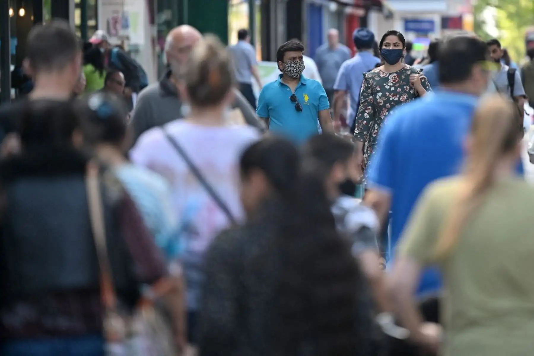 Los peatones, algunos con máscaras debido al Covid-19, pasan frente a las tiendas de Hounslow, al oeste de Londres. Foto: AFP