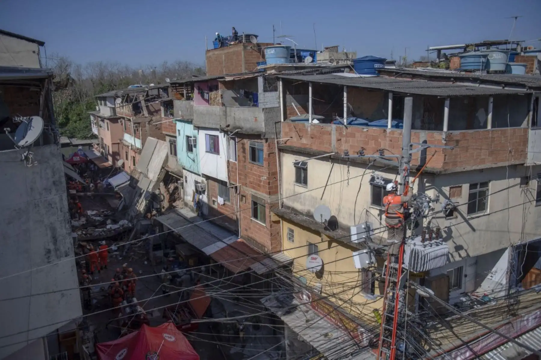 Los trabajadores de la compañía eléctrica apagan la energía mientras los bomberos y los equipos de rescate buscan a las víctimas del derrumbe de un edificio temprano en la mañana en la favela Rio das Pedras en Río de Janeiro el 3 de junio de 2021. Foto: AFP