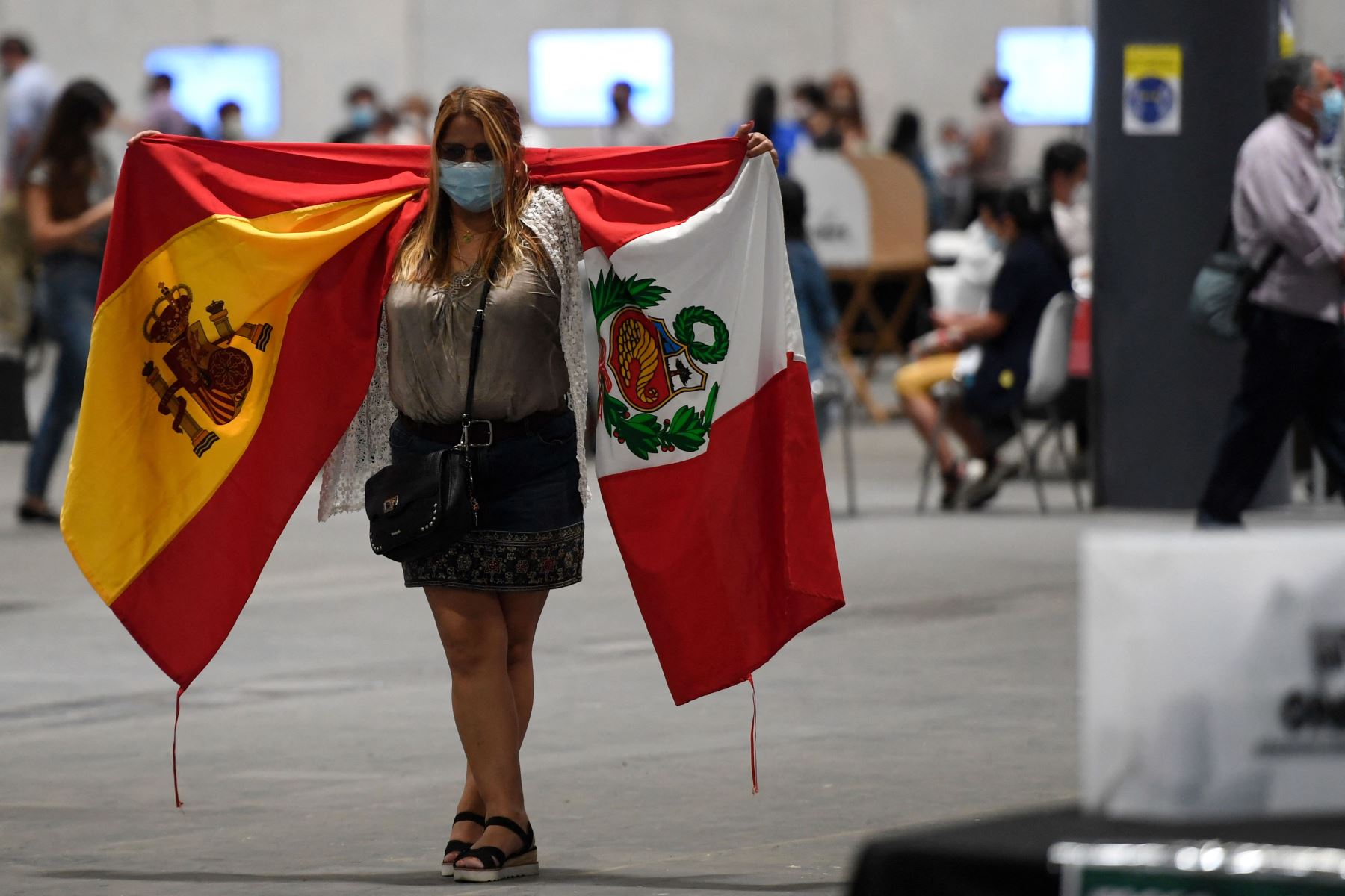 Una residente peruana camina con banderas españolas y peruanas después de emitir su voto para la segunda vuelta de las elecciones presidenciales en un colegio electoral del Palacio de Congresos Ifema en Madrid.
Foto: AFP