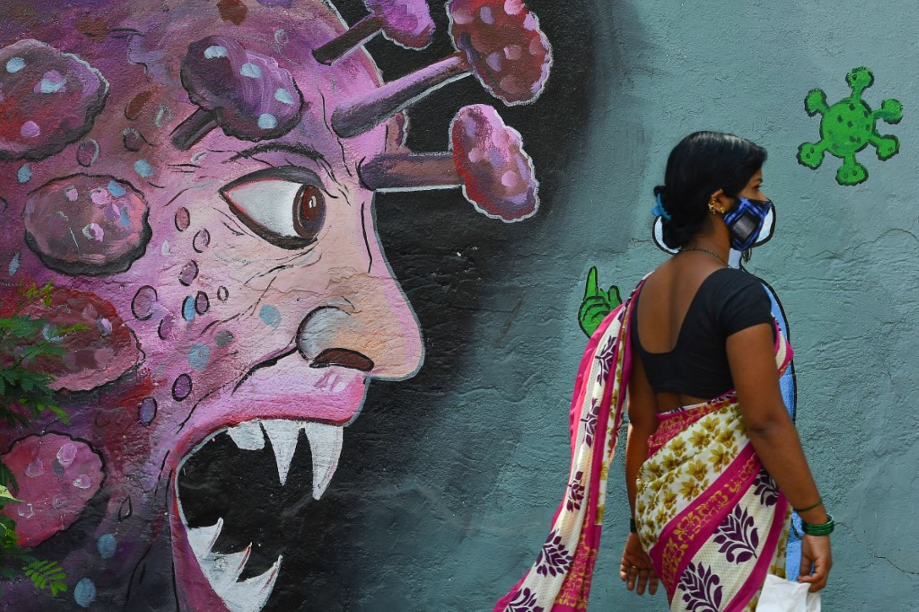Una mujer pasa junto a un mural dedicado a los trabajadores de primera línea que luchan contra la propagación del coronavirus Covid-19 en Navi Mumbai. Foto: AFP