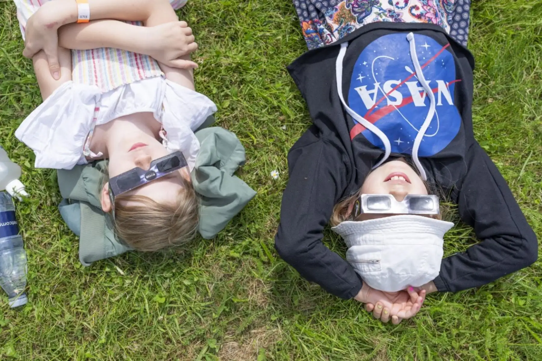 Los niños se acuestan en el césped y miran a través de lentes esperando el eclipse solar parcial en el Observatorio Brorfelde en Tollose, Dinamarca, el 10 de junio de 2021. Foto: AFP