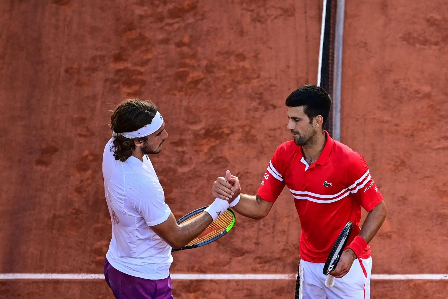 El serbio Novak Djokovic  y el griego Stefanos Tsitsipas se dan la mano al final de su último partido de tenis masculino en el día 15 del torneo de tenis Roland Garros 2021 del Abierto de Francia en París.
Foto: AFP