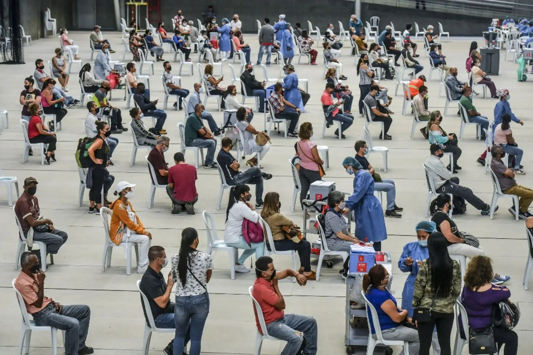 Las personas mayores de 50 años son vacunadas contra covid-19 en un centro de vacunación montado en un campo de voleibol en Medellín, Colombia. Foto: AFP