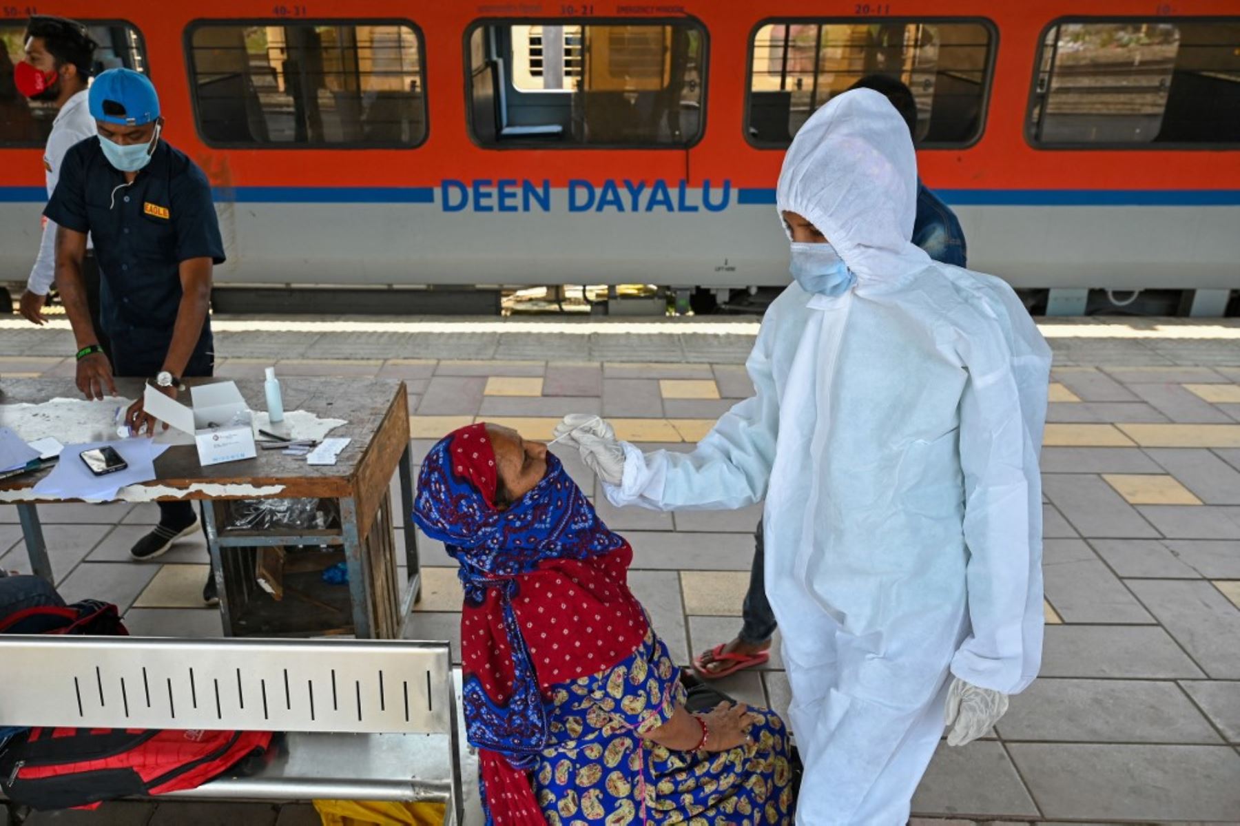 Un trabajador de la salud toma una muestra de hisopado nasal de un pasajero para la prueba del coronavirus covid-19 después de llegar a una plataforma ferroviaria en un tren de larga distancia, en Mumbai, India. Foto: AFP