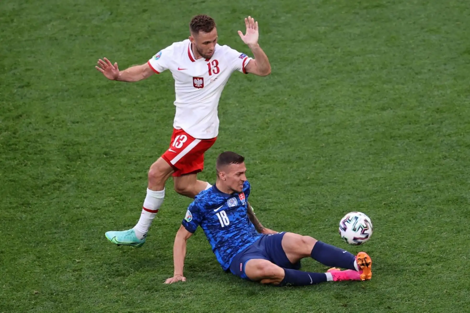 El defensor de Polonia Maciej Rybus (L) y el mediocampista de Eslovaquia Lukas Haraslin compiten por el balón durante el partido de fútbol del Grupo E de la UEFA EURO 2020 entre Polonia y Eslovaquia en el Estadio de San Petersburgo en San Petersburgo el 14 de junio de 2021. Foto: AFP