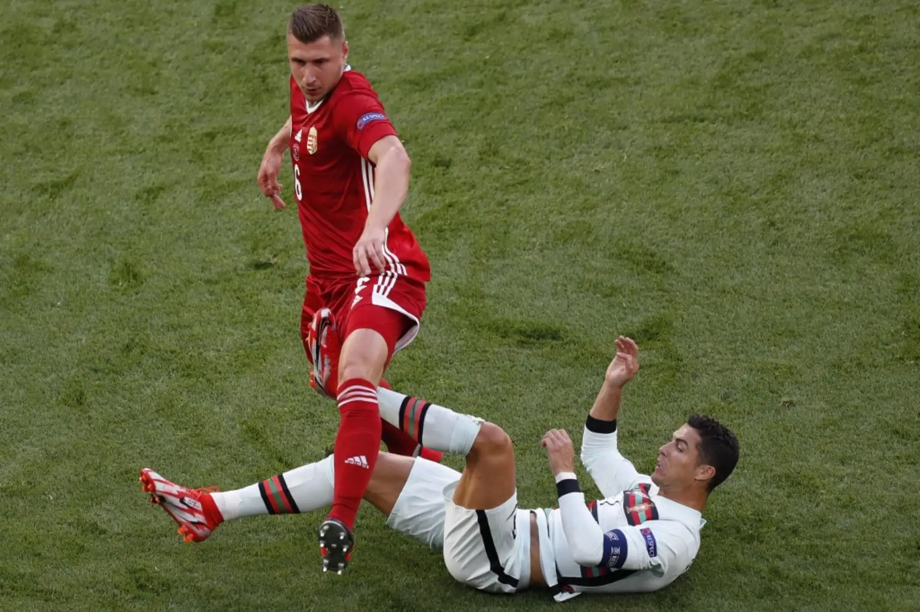 El defensor de Hungría Willi Orban comete una falta al delantero portugués Cristiano Ronaldo (abajo) durante el partido de fútbol del Grupo F de la UEFA EURO 2020 entre Hungría y Portugal en el Puskas Arena de Budapest el 15 de junio de 2021. Foto: AFP