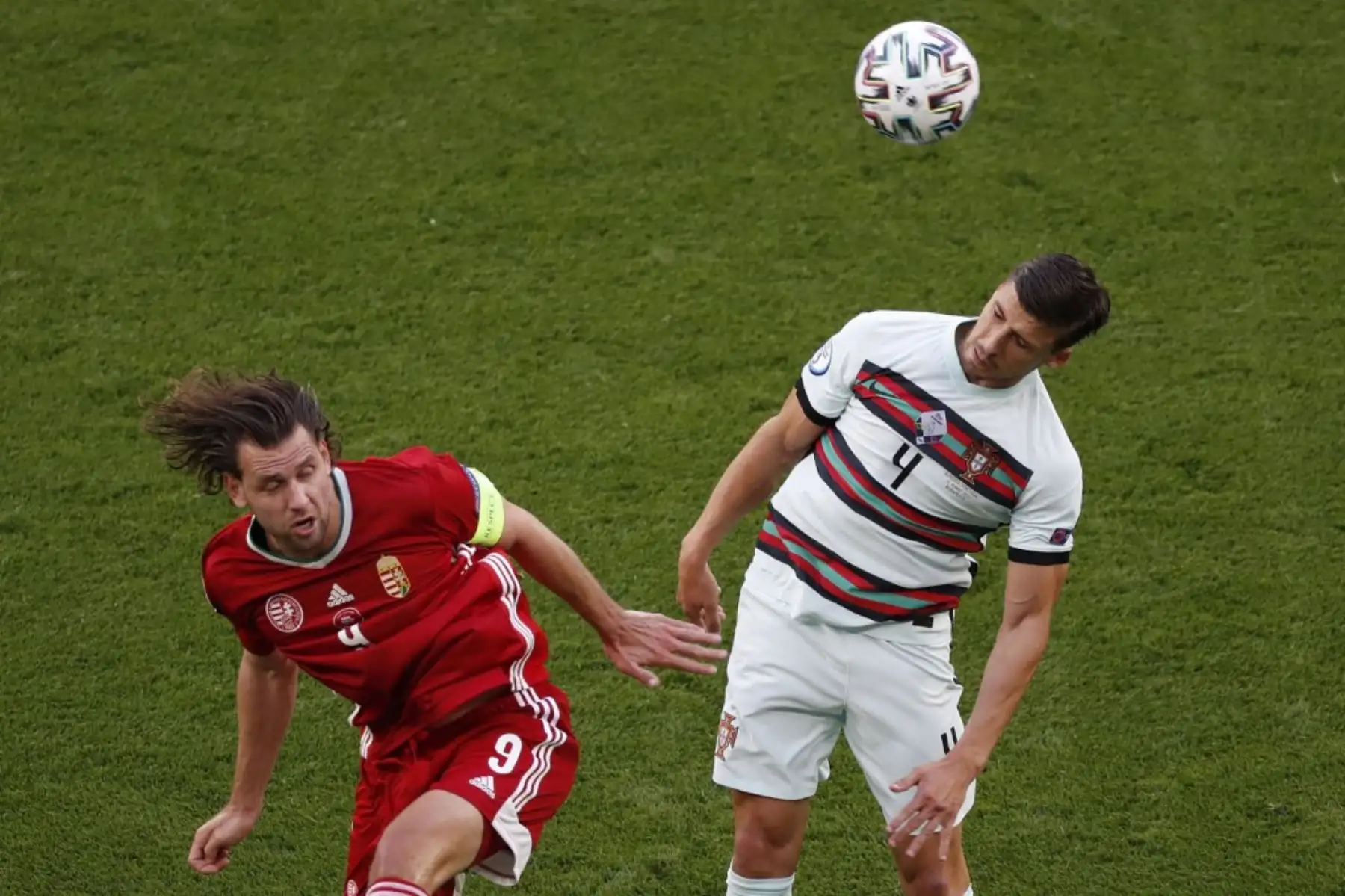 El delantero de Hungría Adam Szalai (L) cabecea el balón con el defensor de Portugal Ruben Dias durante el partido de fútbol del Grupo F de la UEFA EURO 2020 entre Hungría y Portugal en el Puskas Arena de Budapest el 15 de junio de 2021. Foto: AFP