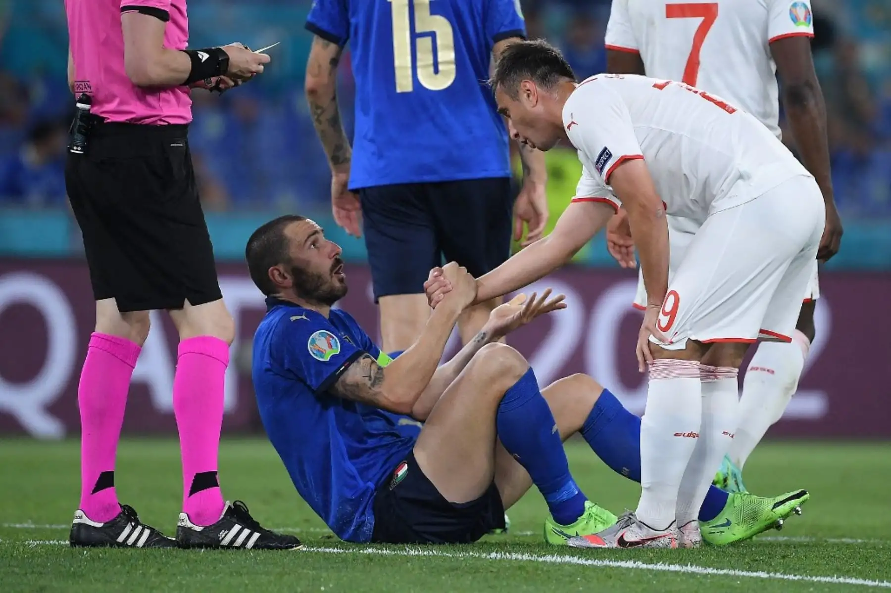 El defensa italiano Leonardo Bonucci (C) es ayudado a ponerse de pie por el delantero suizo Mario Gavranovic (R) durante el partido de fútbol del Grupo A de la UEFA EURO 2020 entre Italia y Suiza en el Estadio Olímpico de Roma el 16 de junio de 2021. Foto: AFP
