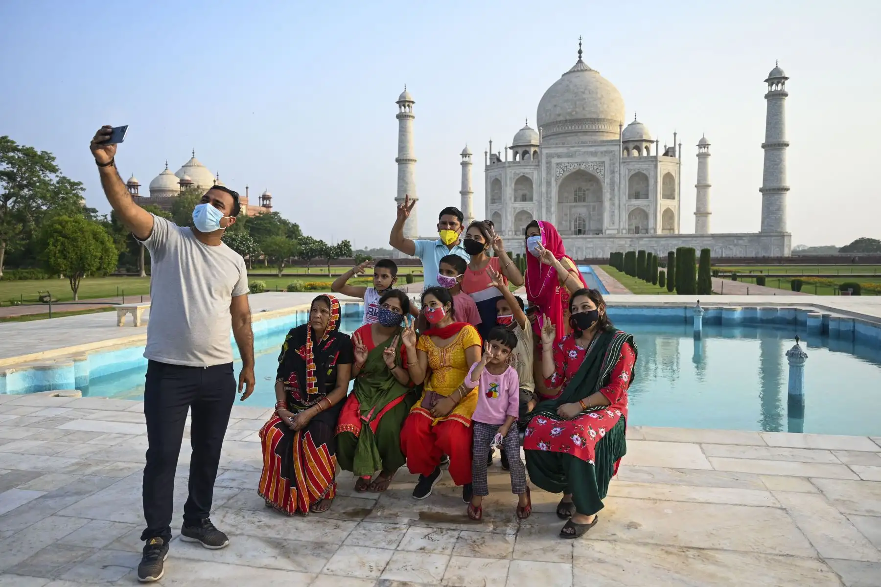 Un grupo de turistas toma fotos de recuerdo en el Taj Mahal después de que reabrió a los visitantes luego de que las autoridades flexibilizaran las restricciones del covid-19 en Agra.
Foto: AFP