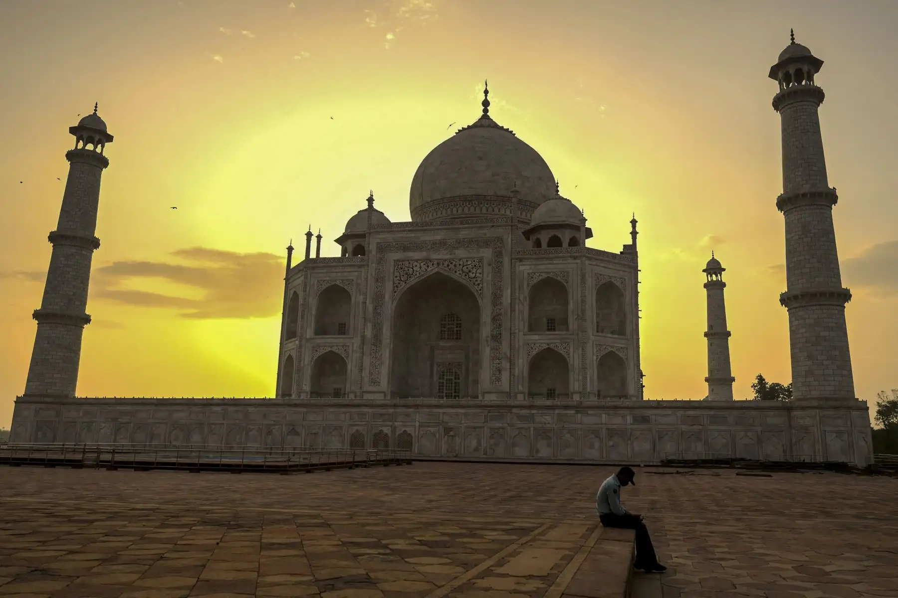 Un guardia de seguridad se toma un descanso cuando sale el sol detrás del Taj Mahal después de que reabriera a los visitantes luego de que las autoridades suavizaran las restricciones del coronavirus  en Agra.
Foto: AFP