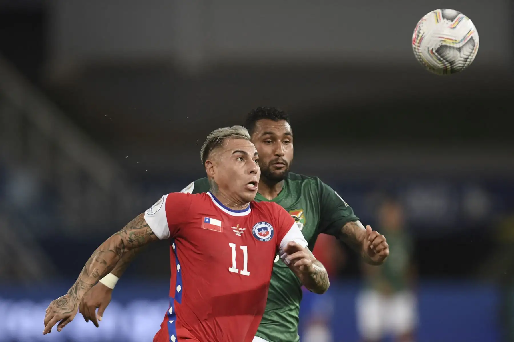 El chileno Eduardo Vargas y el boliviano Adrián Jusino compiten por el balón durante el partido de la fase de grupos de la Copa América, en el Pantanal Arena de Cuiabá, Brasil. Foto: AFP