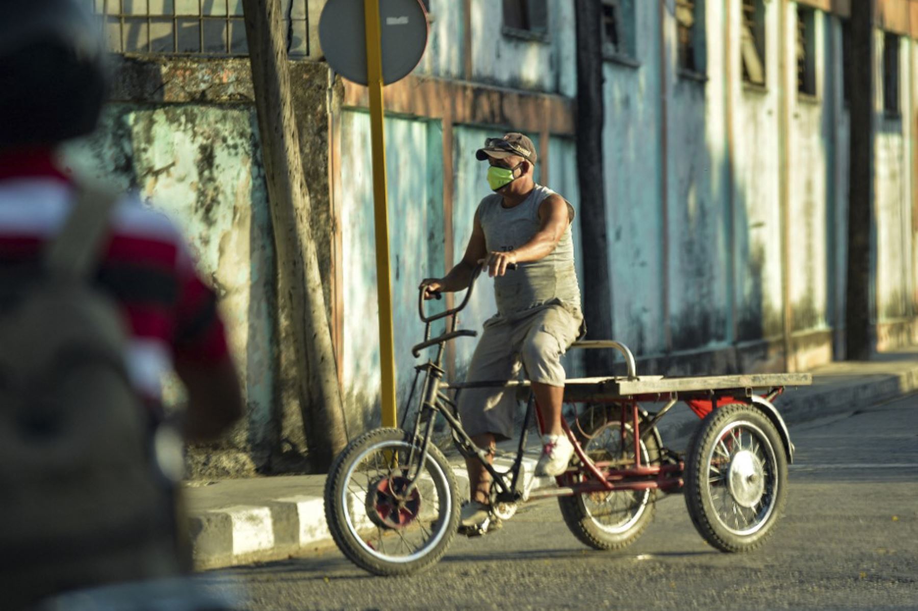 Hombre con mascarilla anda en bicicleta por una calle de La Habana. Foto: AFP