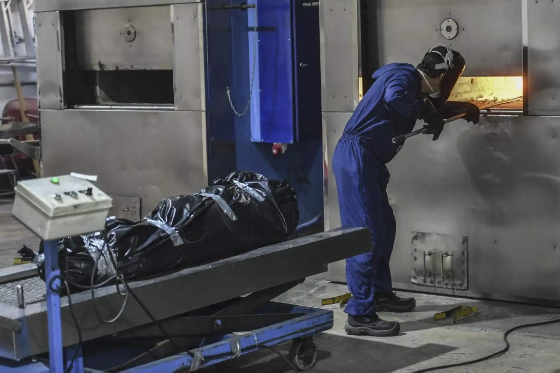 El operador del crematorio Omar Giraldo maneja un incinerador mientras se muestra el cuerpo de una persona que murió de Covid-19 detrás en el cementerio de Campos de Paz, en Medellín, Colombia. Foto: AFP