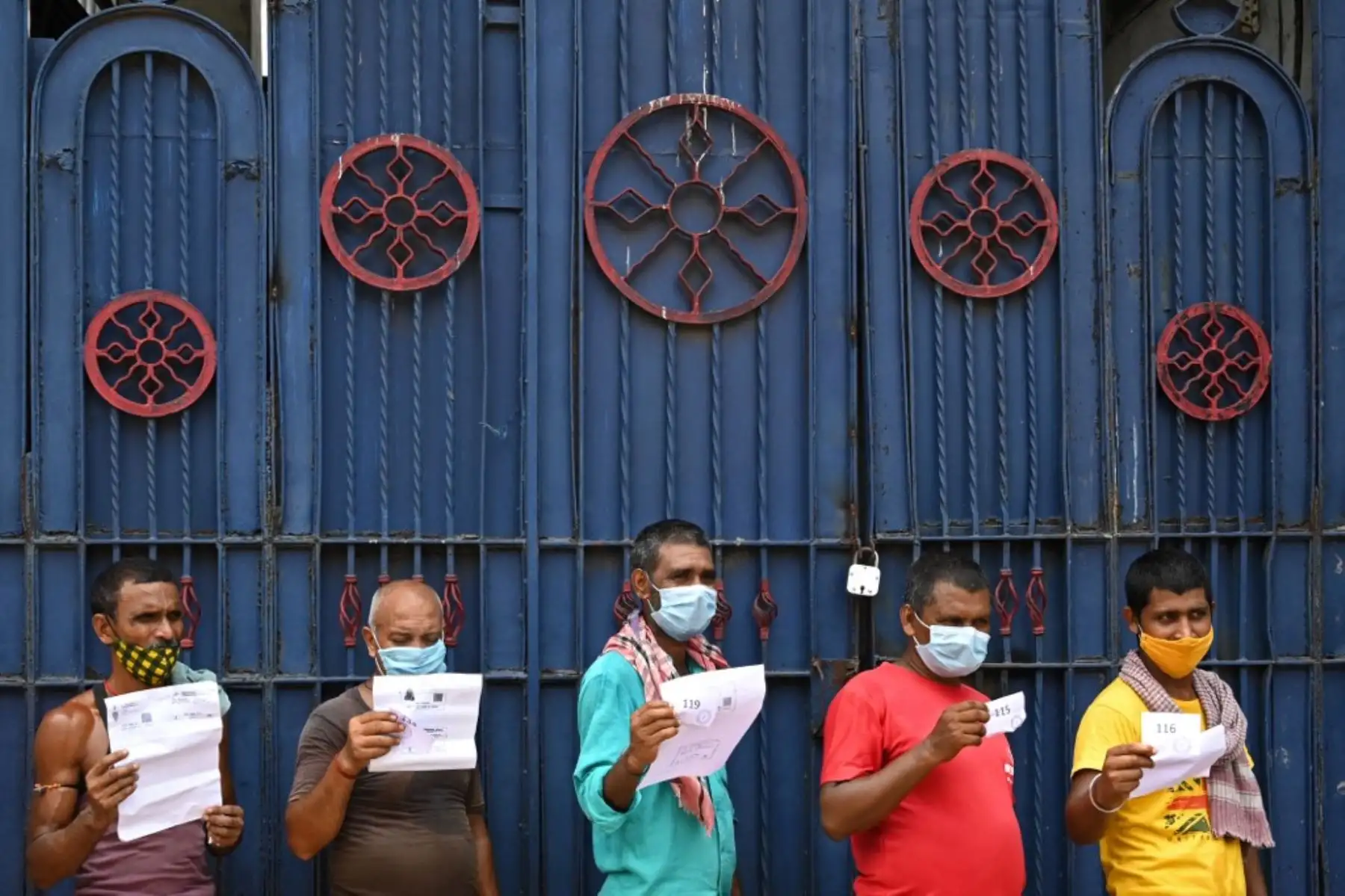 Los trabajadores sostienen documentos mientras esperan su turno para recibir la primera dosis de la vacuna Covishield contra el coronavirus Covid-19 en un autobús de pasajeros convertido en un centro de vacunación móvil en un mercado mayorista en Calcuta. Foto: AFP