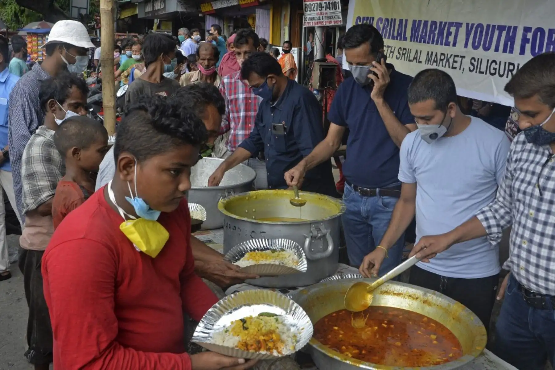 Las personas que en su mayoría son jornaleros que han perdido oportunidades de trabajo durante los tiempos del encierro y los que pertenecen al segmento de la sociedad por debajo del umbral de pobreza hacen cola para recibir comidas gratuitas distribuidas por voluntarios en Siliguri. Foto: AFP