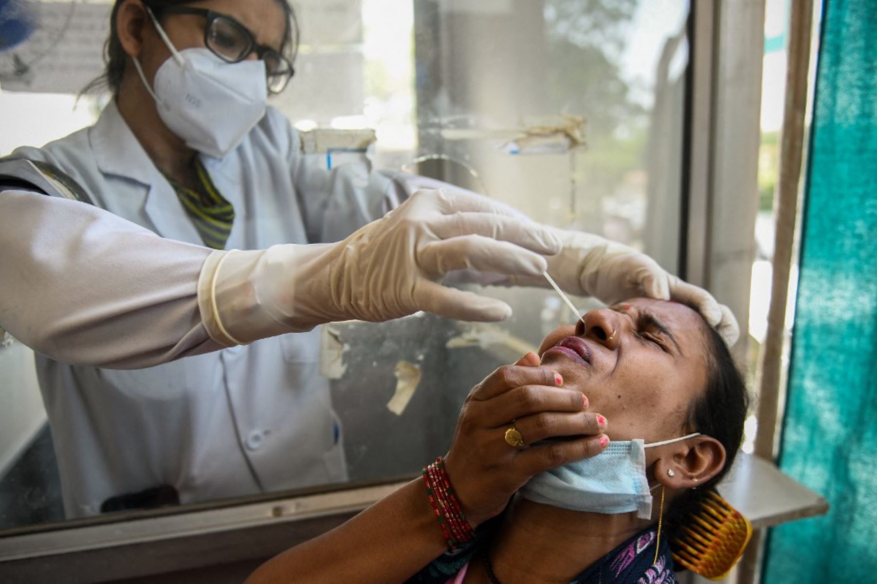 Un trabajador de la salud toma una muestra de frotis nasal de una mujer durante una prueba de detección del coronavirus Covid-19 que se llevó a cabo en Amritsar. Foto: AFP