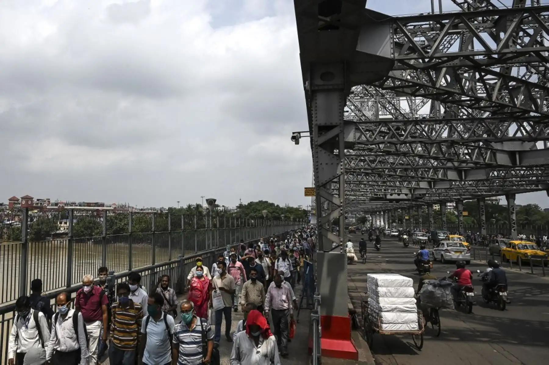 Los viajeros caminan mientras cruzan el puente Howrah mientras el gobierno estatal suspendió el transporte público regular durante un bloqueo impuesto para frenar la propagación del coronavirus Covid-19, en Calcuta. Foto: AFP