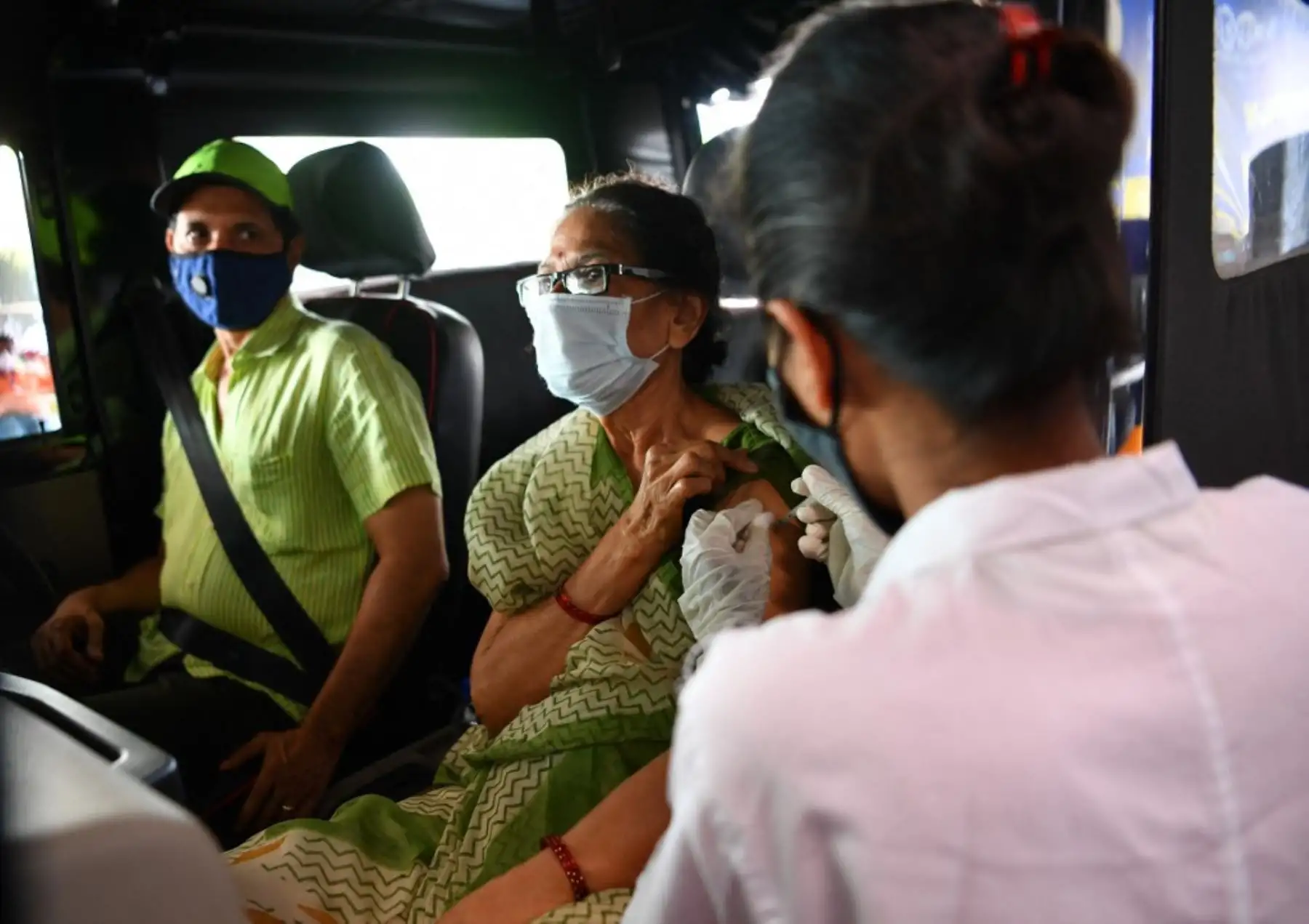 Un trabajador de salud inocula a una mujer con una dosis de una vacuna contra el coronavirus Covid-19, en un centro de vacunación dentro de un centro comercial en Mumbai. Foto: AFP