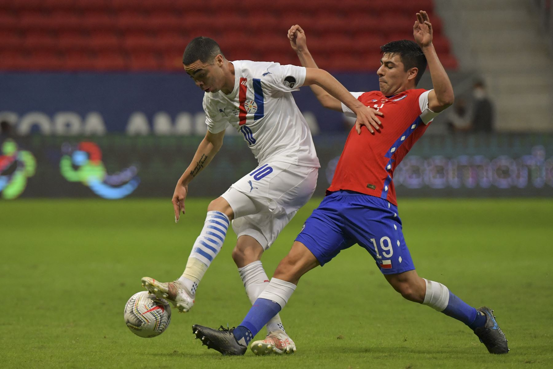 Miguel Almirón de Paraguay y Tomás Alarcón de Chile compiten por el balón durante el partido de la fase de grupos de la Copa América 2021, en el estadio Mane Garrincha de Brasilia. Foto: AFP